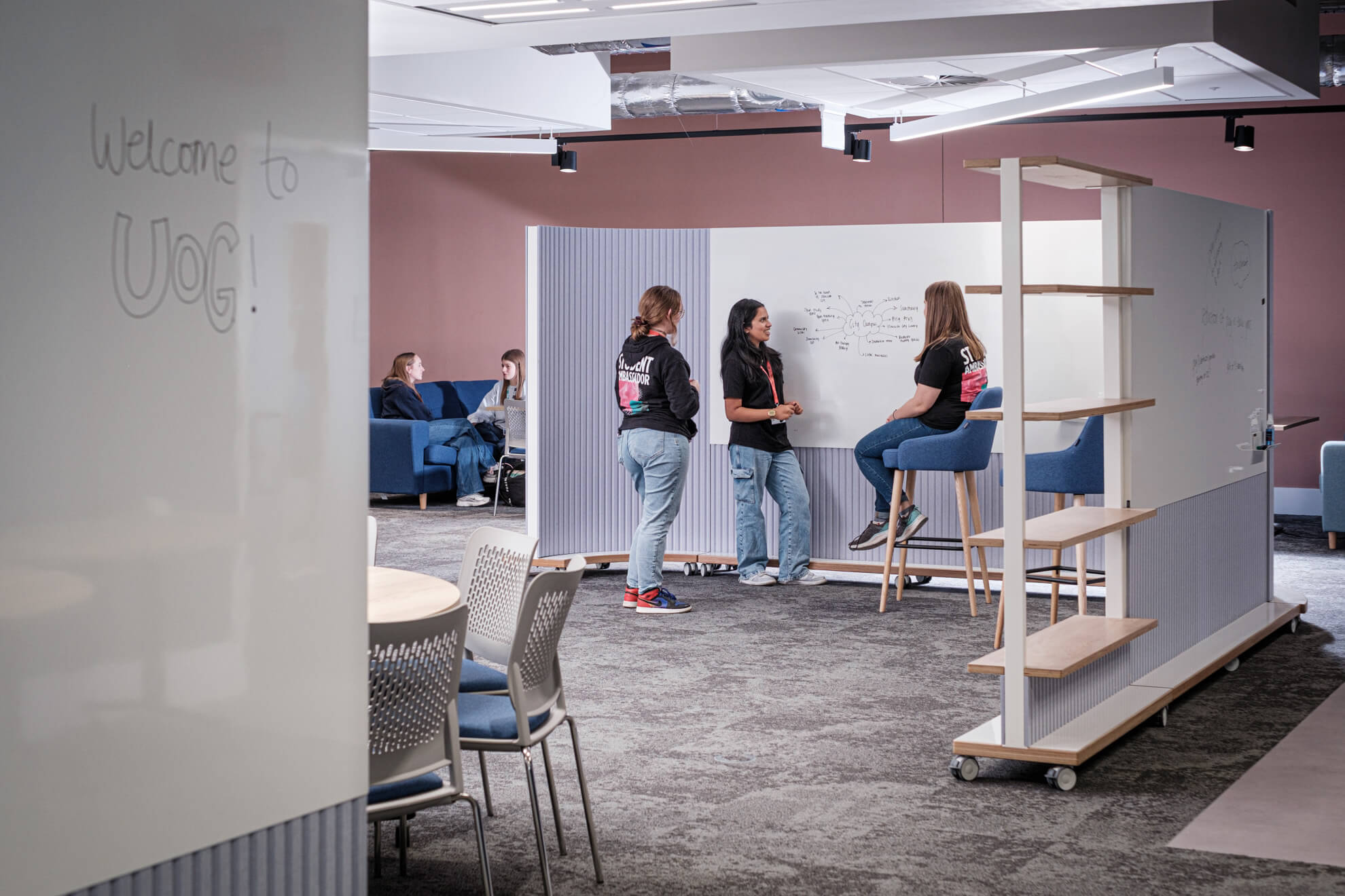 small group of students stand at a whiteboard